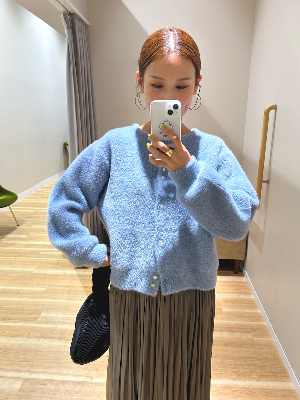 ブルー系のカーディガン/ボレロ、ベージュ系のスカート、ブラック系のハンドバッグを着用したレディースの秋コーディネートの4枚目の写真