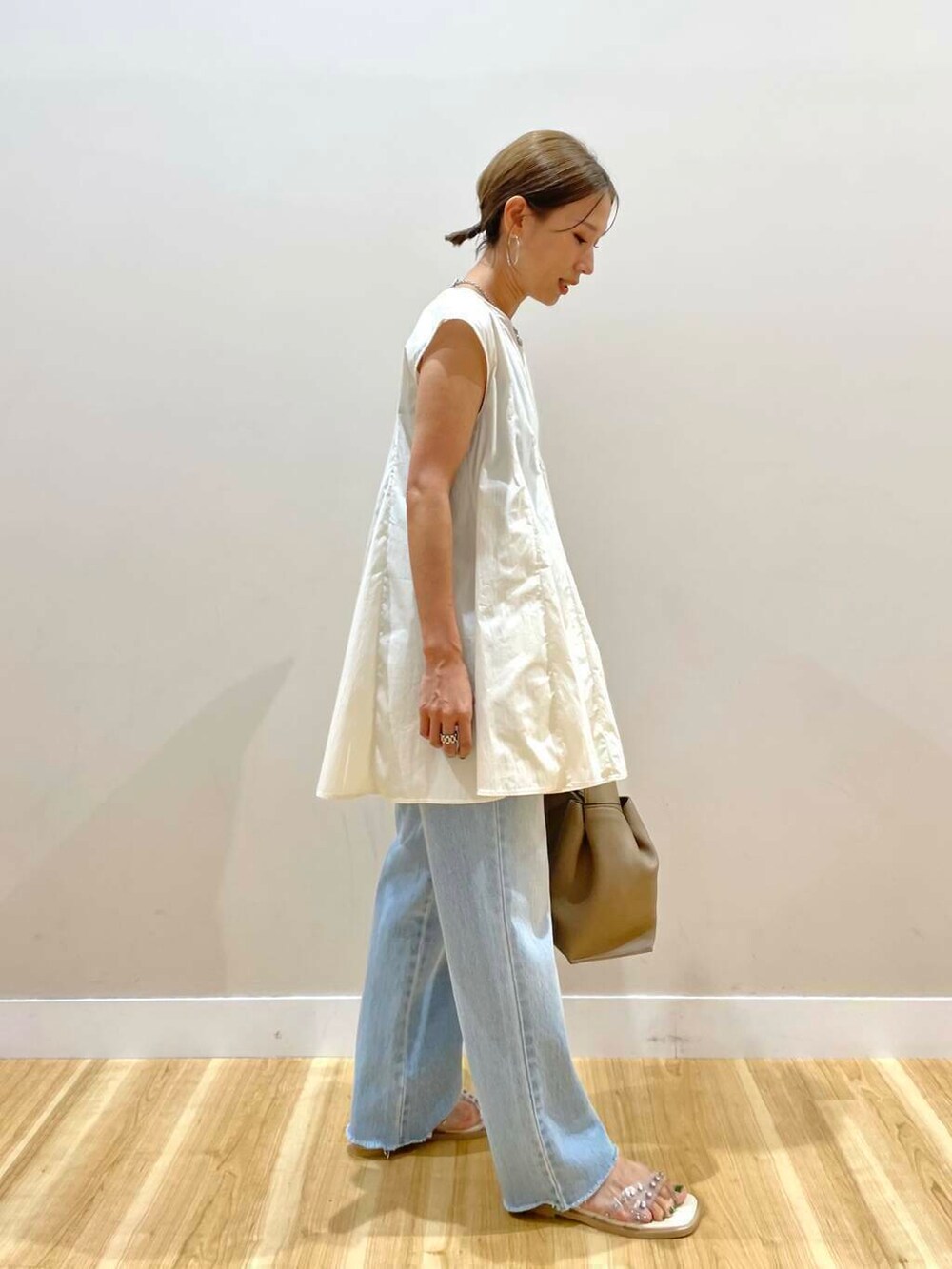 ホワイト系のサンダル、ブルー系のデニムパンツ、ベージュ系のハンドバッグを着用したレディースの夏コーディネートの2枚目の写真