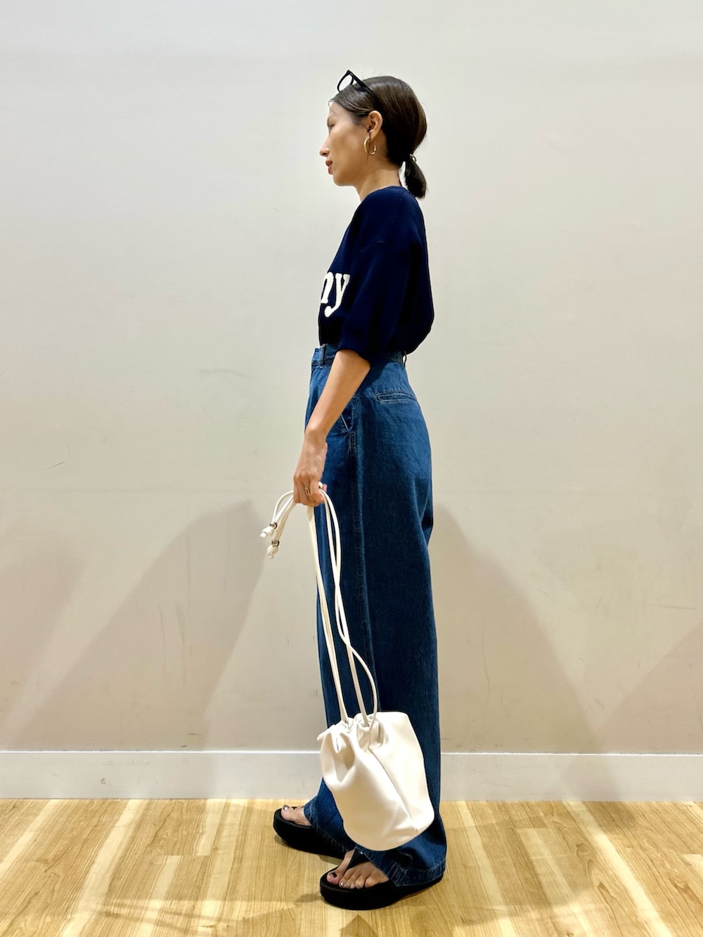 ブルー系のニット/セーター、ブルー系のデニムパンツ、ホワイト系のショルダーバッグを着用したレディースの夏コーディネートの3枚目の写真