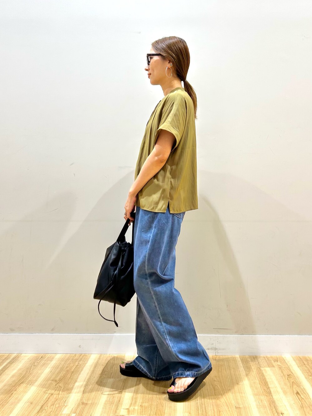 イエロー系のシャツ/ブラウス、ブルー系のデニムパンツ、ブラック系のショルダーバッグを着用したレディースの夏コーディネートの4枚目の写真