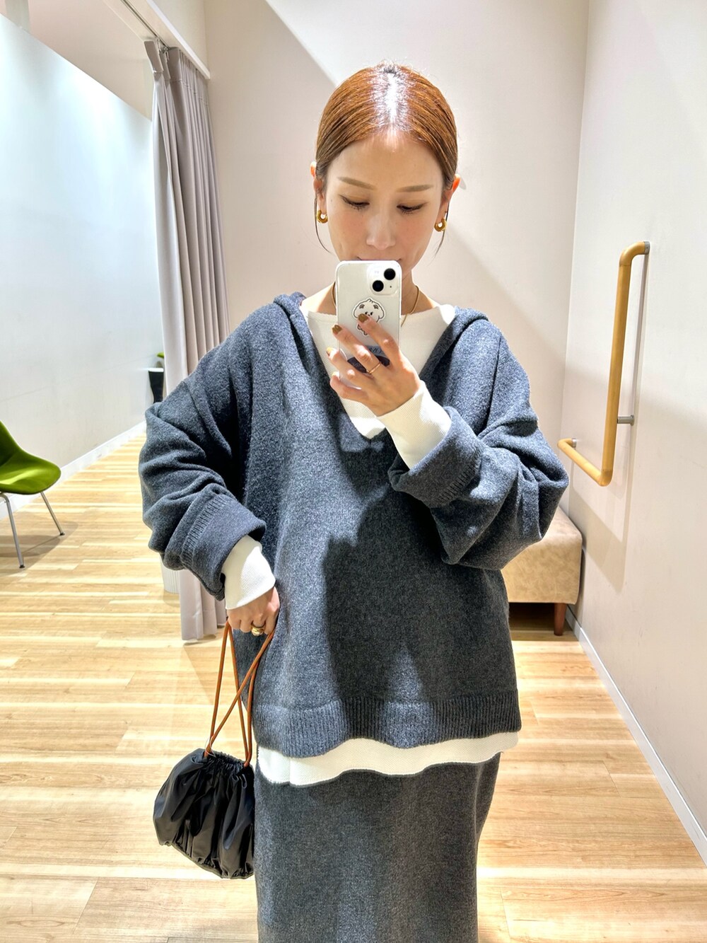 グレー系のニット/セーター、ホワイト系のTシャツ/カットソー、グレー系のスカートを着用したレディースの秋コーディネートの5枚目の写真