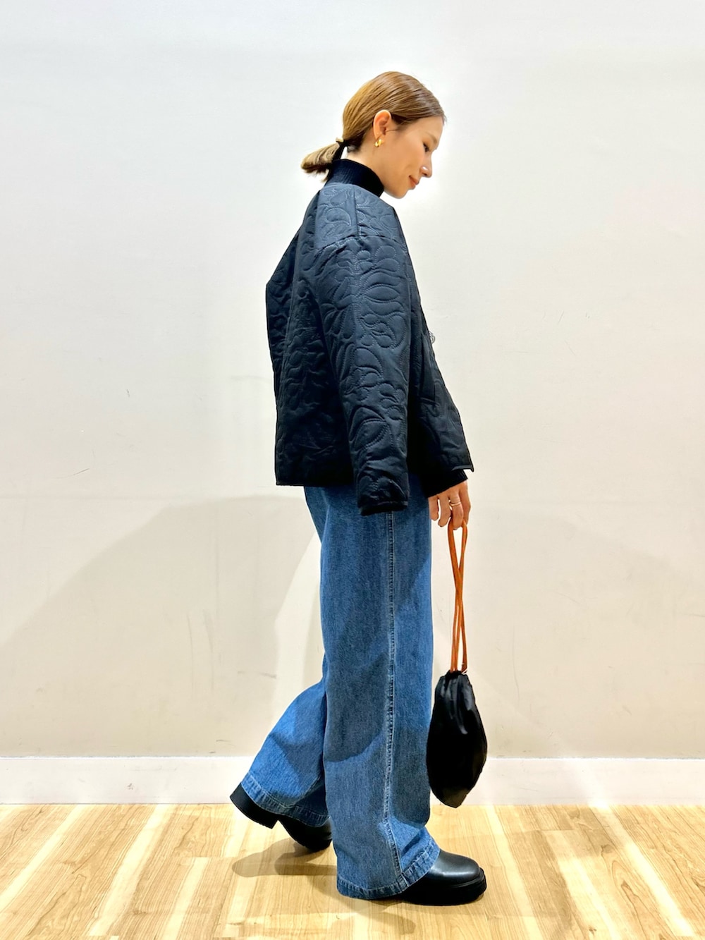 ブラック系のノーカラージャケット、ホワイト系のニット/セーター、ブルー系のデニムパンツを着用したレディースの秋コーディネートの2枚目の写真