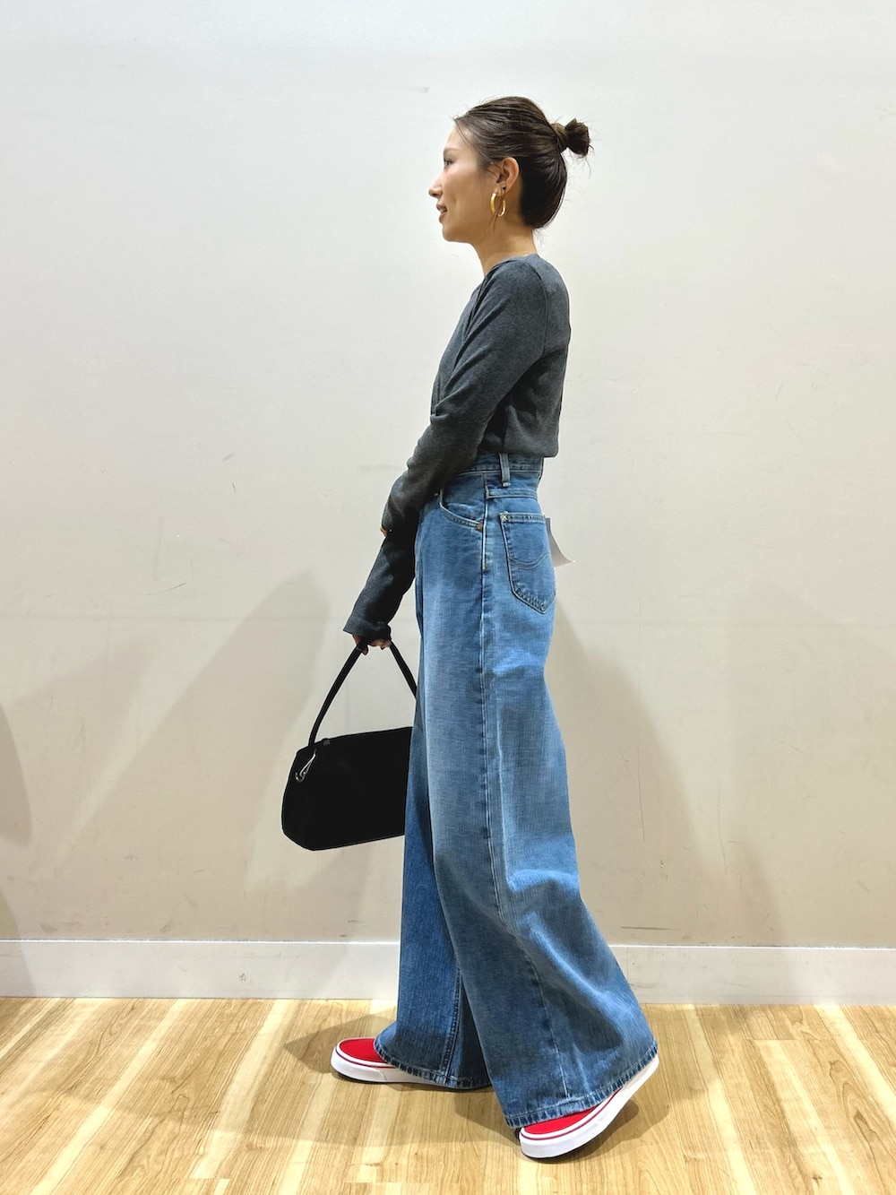 グレー系のステンカラーコート、グレー系のTシャツ/カットソー、ブルー系のデニムパンツを着用したレディースの春コーディネートの6枚目の写真