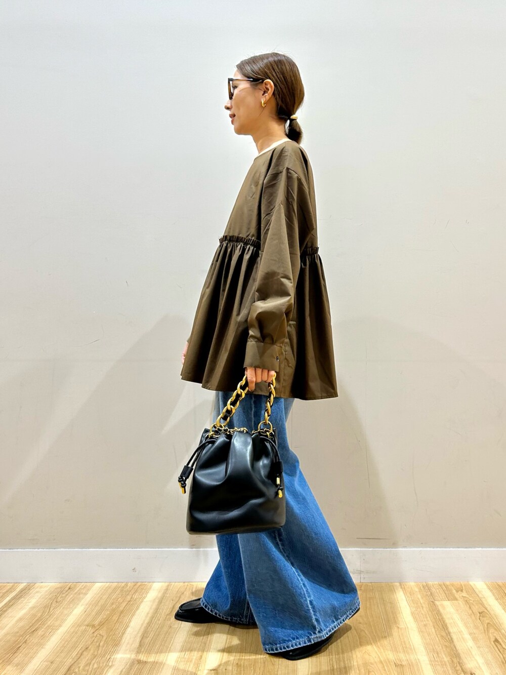 ブラウン系のシャツ/ブラウス、ブルー系のデニムパンツ、ブラック系のショルダーバッグを着用したレディースの秋コーディネートの5枚目の写真