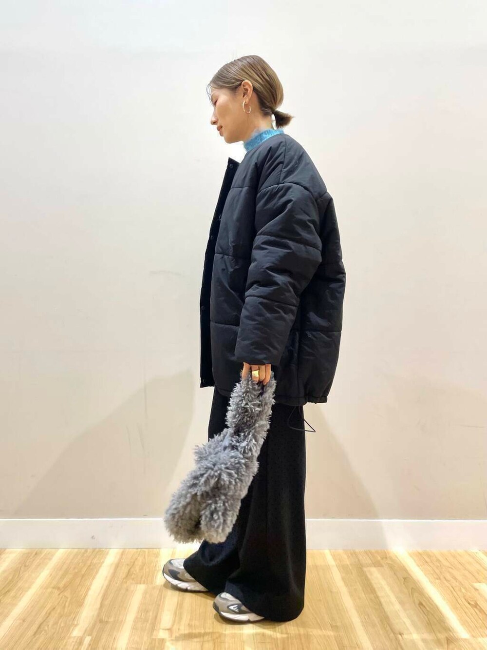 ブラック系のダウンジャケット/コート、ブルー系のニット/セーター、グレー系のハンドバッグを着用したレディースの冬コーディネートの4枚目の写真