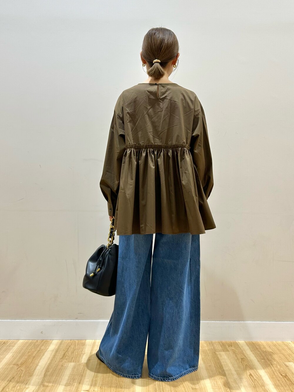 ブラウン系のシャツ/ブラウス、ブルー系のデニムパンツ、ブラック系のショルダーバッグを着用したレディースの秋コーディネートの3枚目の写真