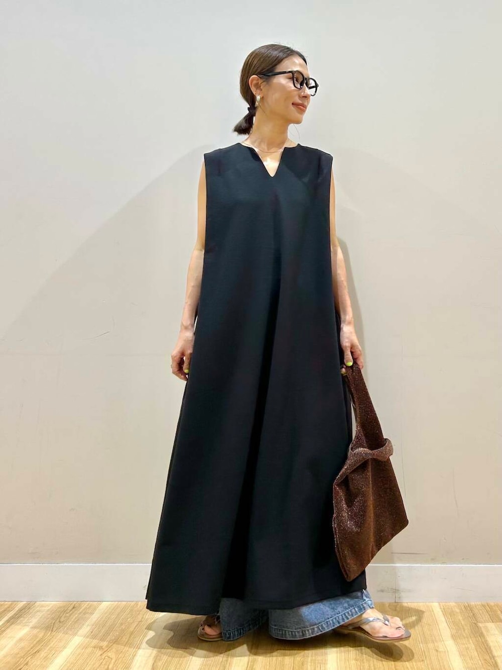 シルバー系のサンダル、ブラウン系のトートバッグ、ブラック系のワンピースを着用したレディースの夏コーディネートの5枚目の写真