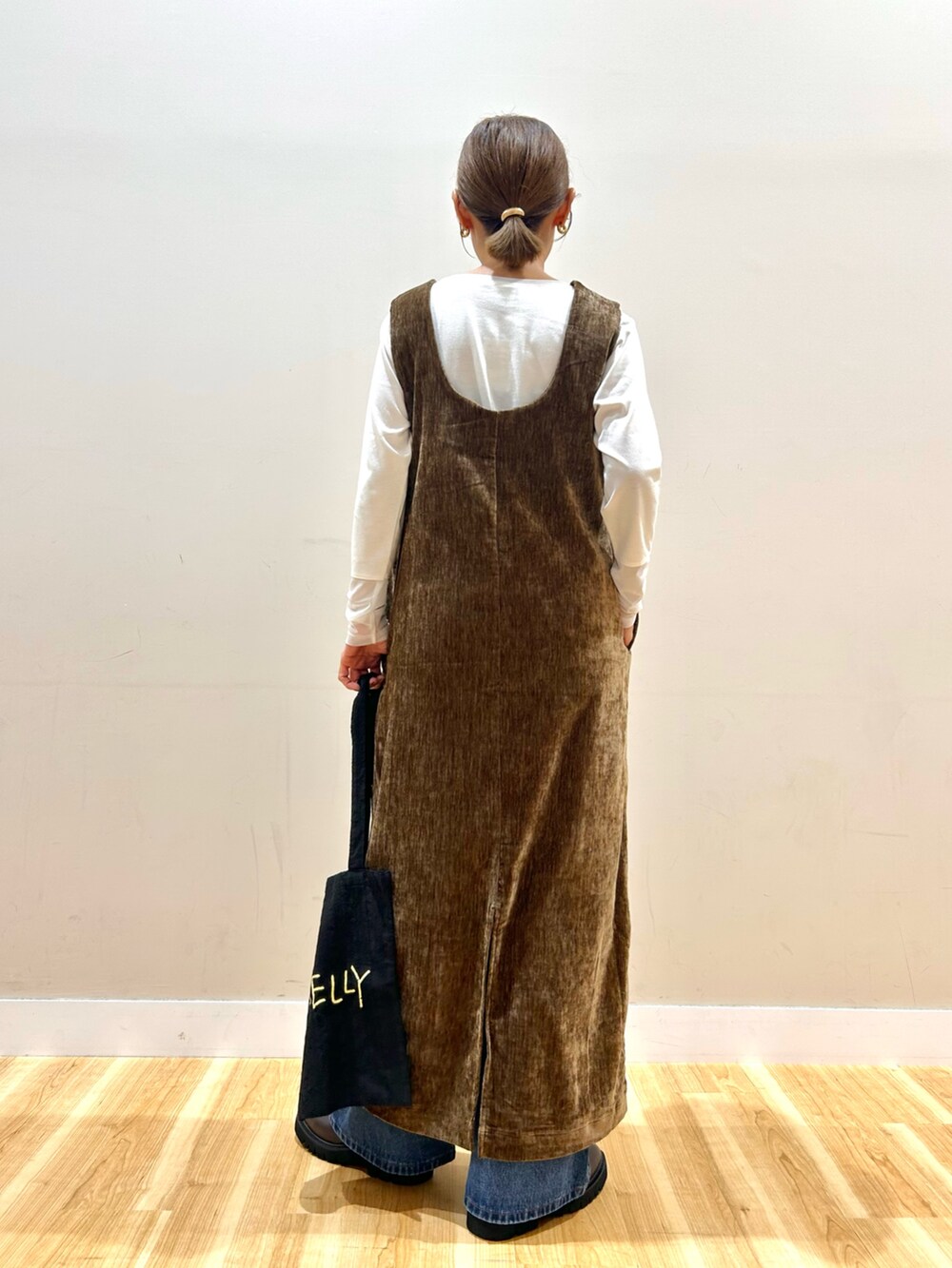 ブラウン系のワンピース、ホワイト系のTシャツ/カットソー、ブラウン系のブーツを着用したレディースの秋コーディネートの3枚目の写真