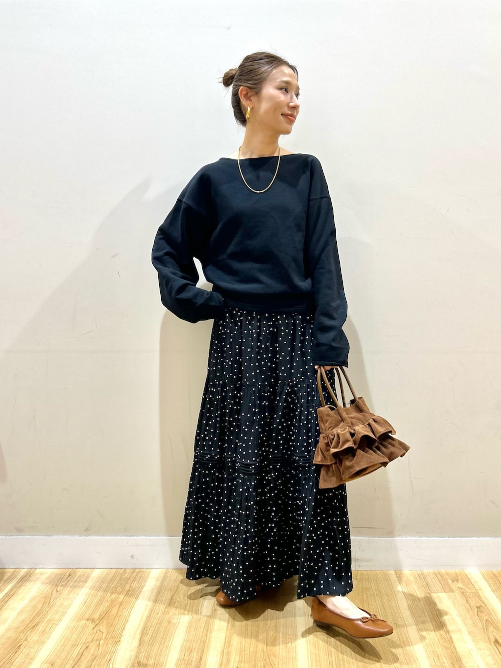 ブラック系のスウェット、ブラック系のスカート、ブラウン系のハンドバッグを着用したレディースの春コーディネートの7枚目の写真