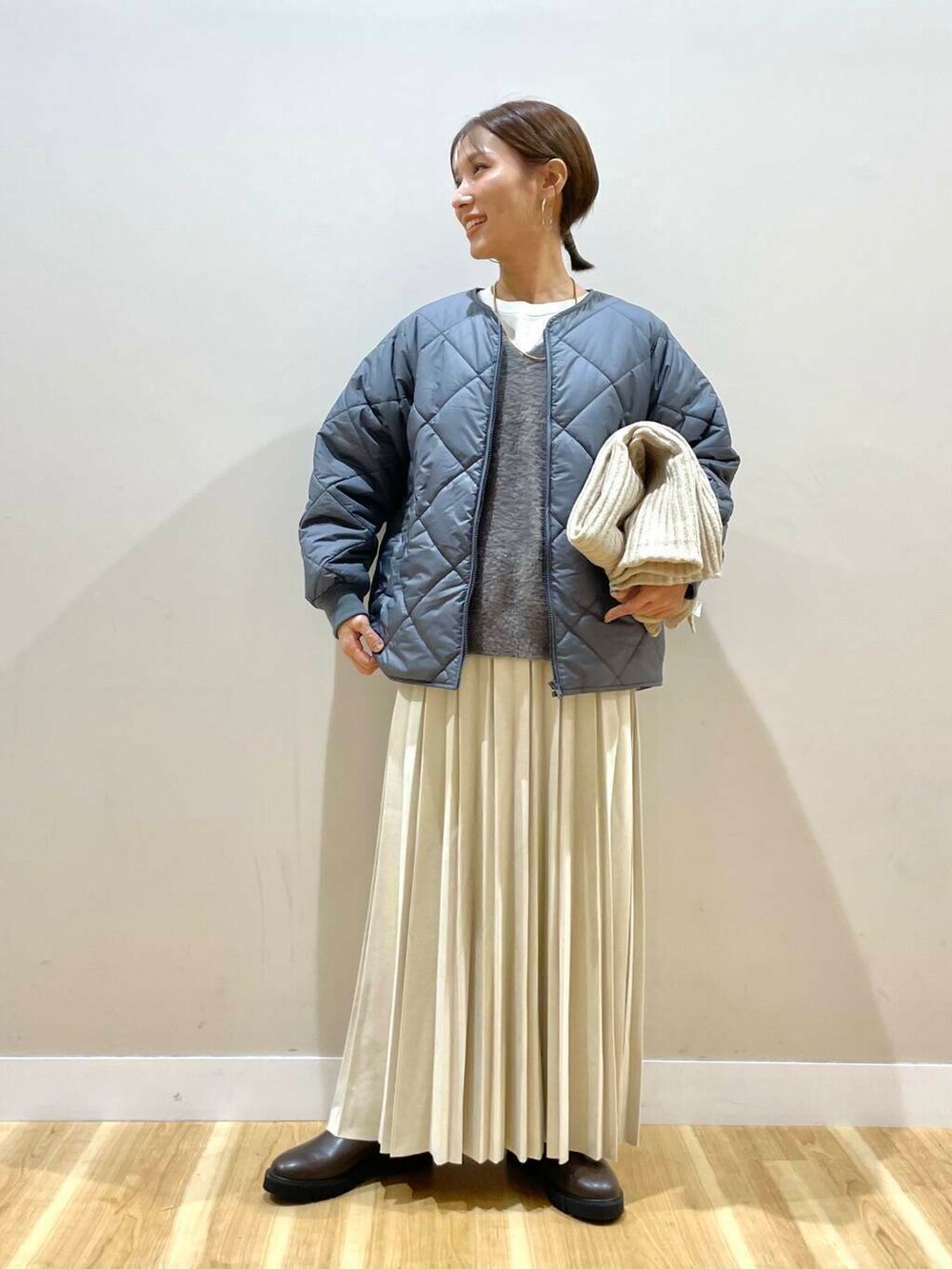 ベージュ系のスカート、ブラック系のブーツ、グレー系のダウンジャケット/コートを着用したレディースの冬コーディネートの6枚目の写真