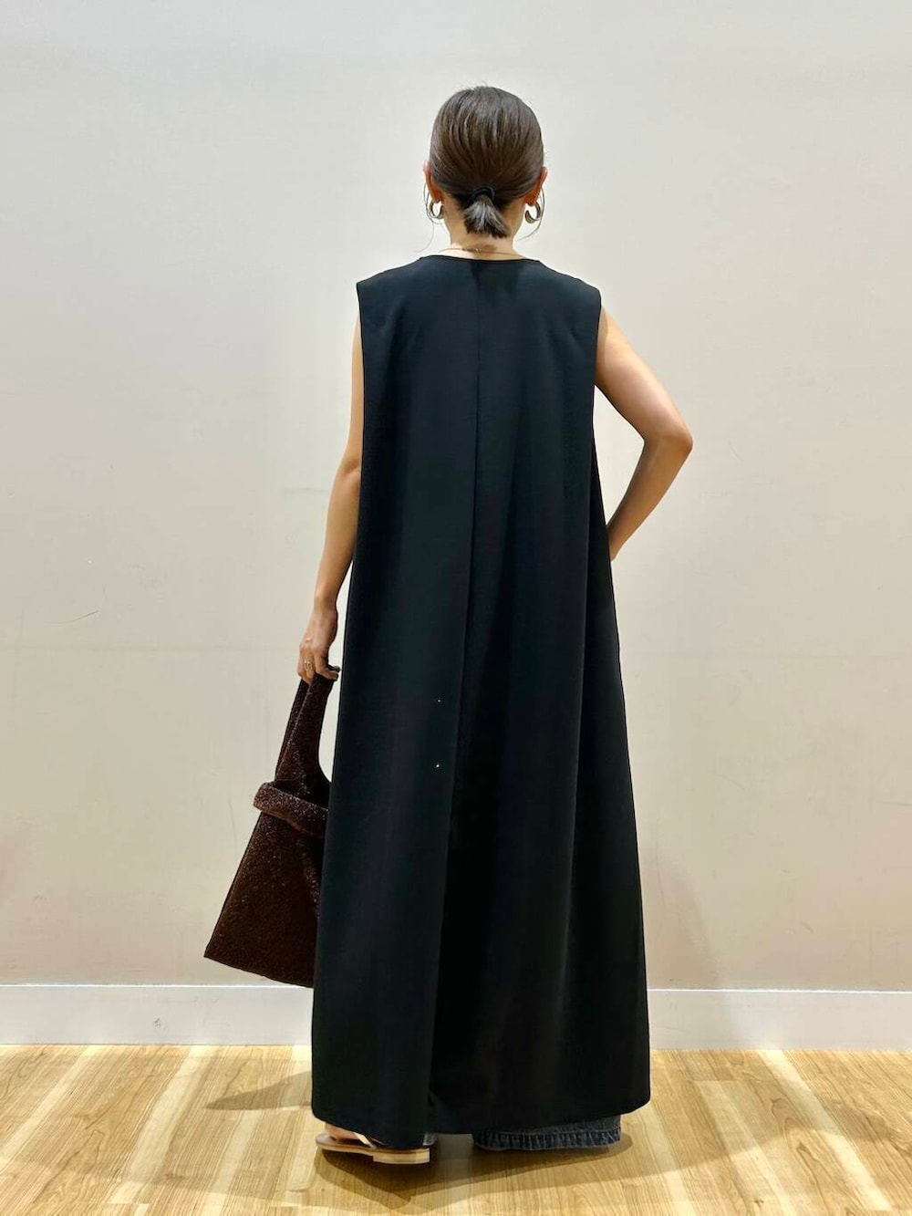 シルバー系のサンダル、ブラウン系のトートバッグ、ブラック系のワンピースを着用したレディースの夏コーディネートの3枚目の写真
