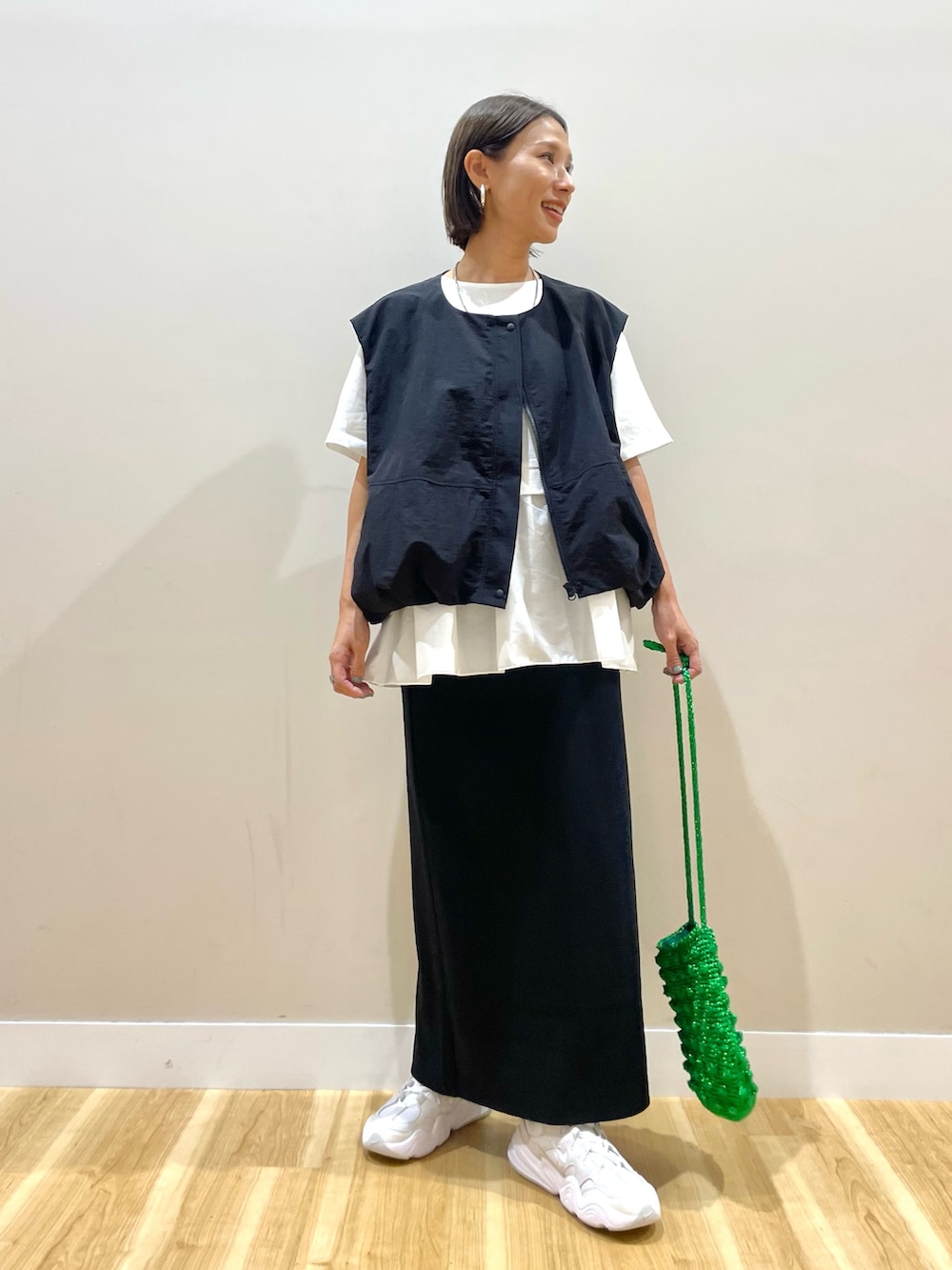 ブラック系のベスト、ホワイト系のTシャツ/カットソー、ブラック系のスカートを着用したレディースの秋コーディネートの5枚目の写真