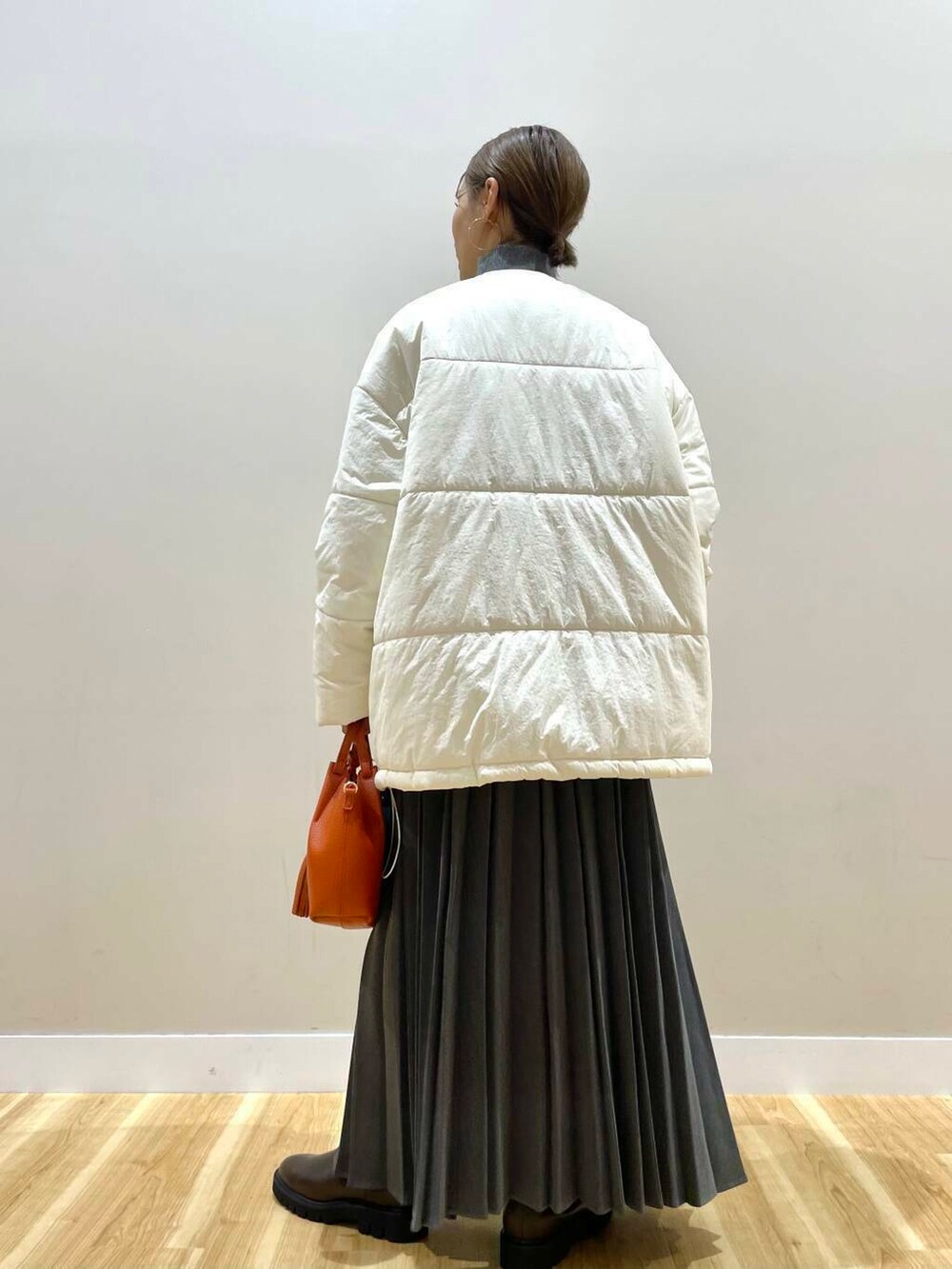 ブラウン系のブーツ、オレンジ系のショルダーバッグ、グレー系のスカートを着用したレディースの冬コーディネートの5枚目の写真