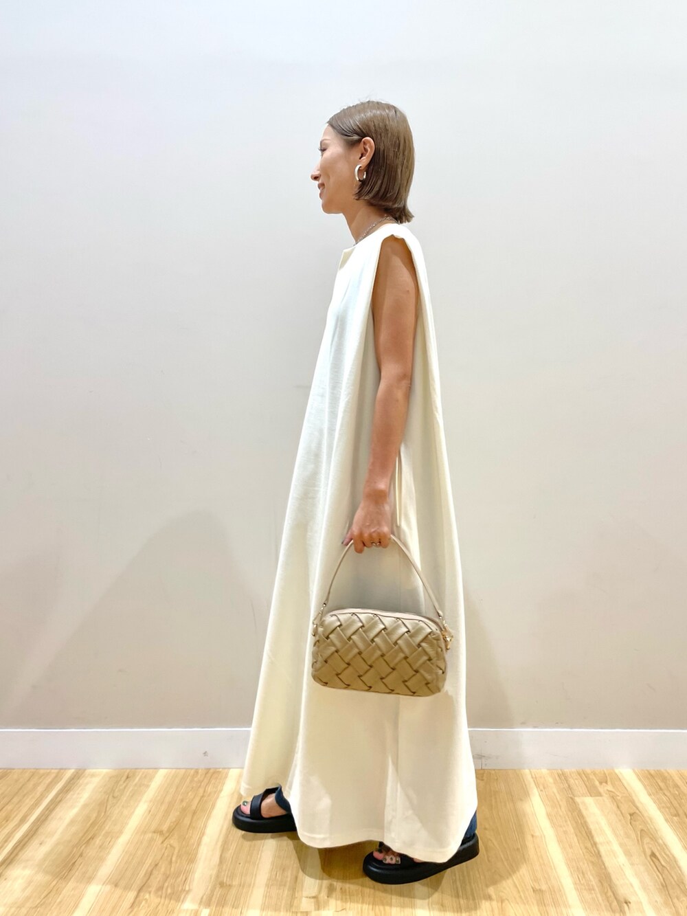 ホワイト系のワンピース、ベージュ系のショルダーバッグ、ブルー系のデニムパンツを着用したレディースの夏コーディネートの3枚目の写真