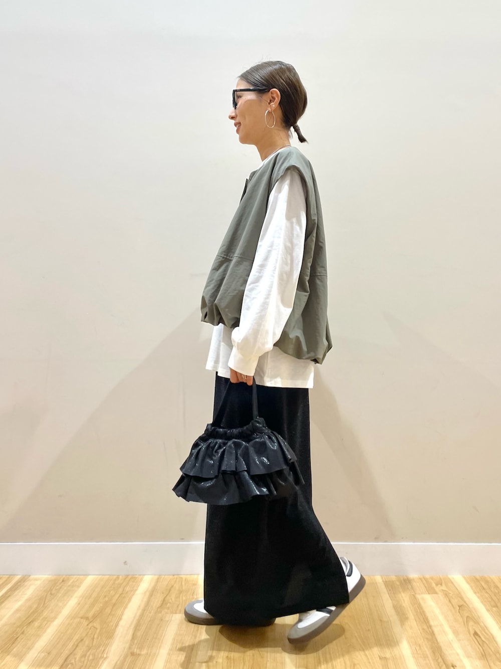 グリーン系のベスト、ホワイト系のTシャツ/カットソー、ブラック系のスカートを着用したレディースの秋コーディネートの2枚目の写真