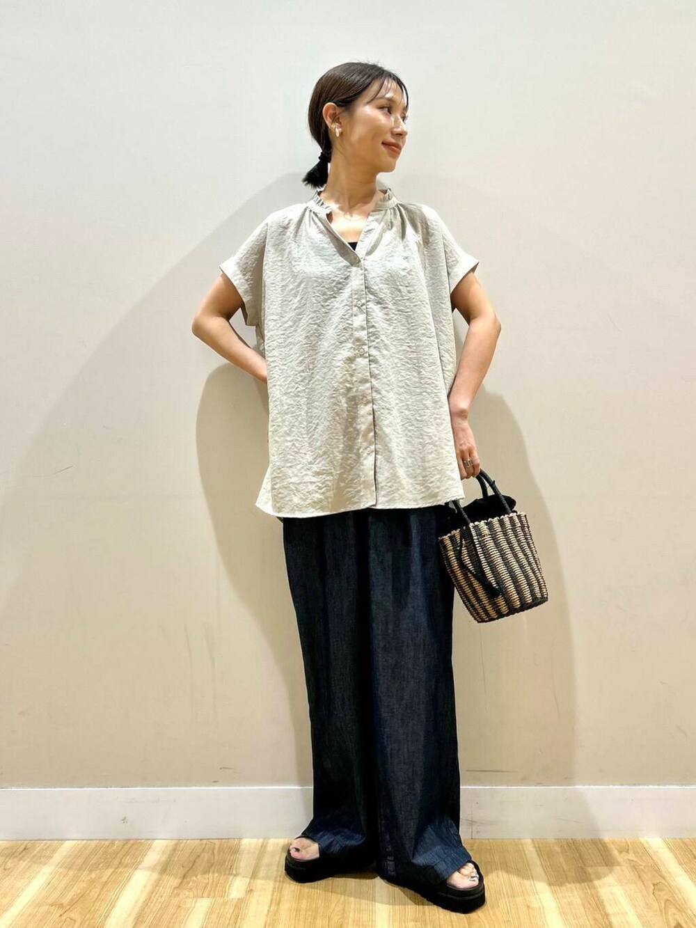 ブラック系のハンドバッグ、ブラック系のサンダル、ブルー系のデニムパンツを着用したレディースの夏コーディネートの5枚目の写真