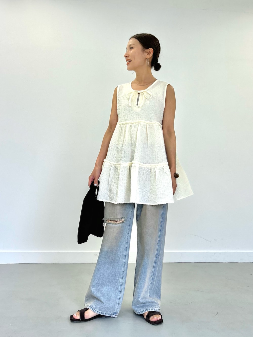 ブルー系のデニムパンツ、ホワイト系のチュニックを着用したレディースの春コーディネートの6枚目の写真