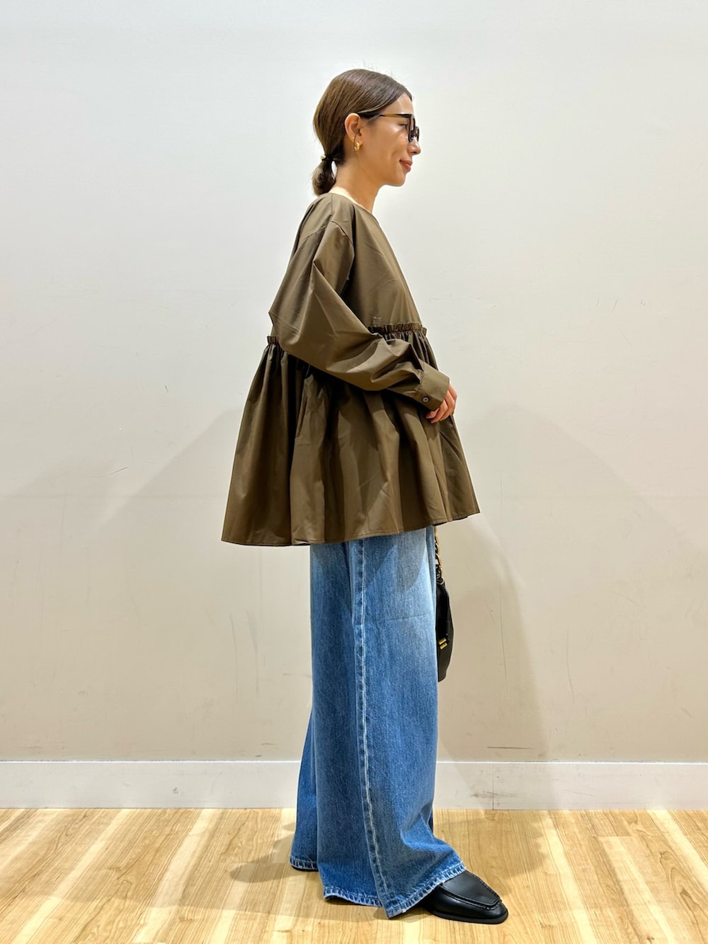 ブラウン系のシャツ/ブラウス、ブルー系のデニムパンツ、ブラック系のショルダーバッグを着用したレディースの秋コーディネートの2枚目の写真