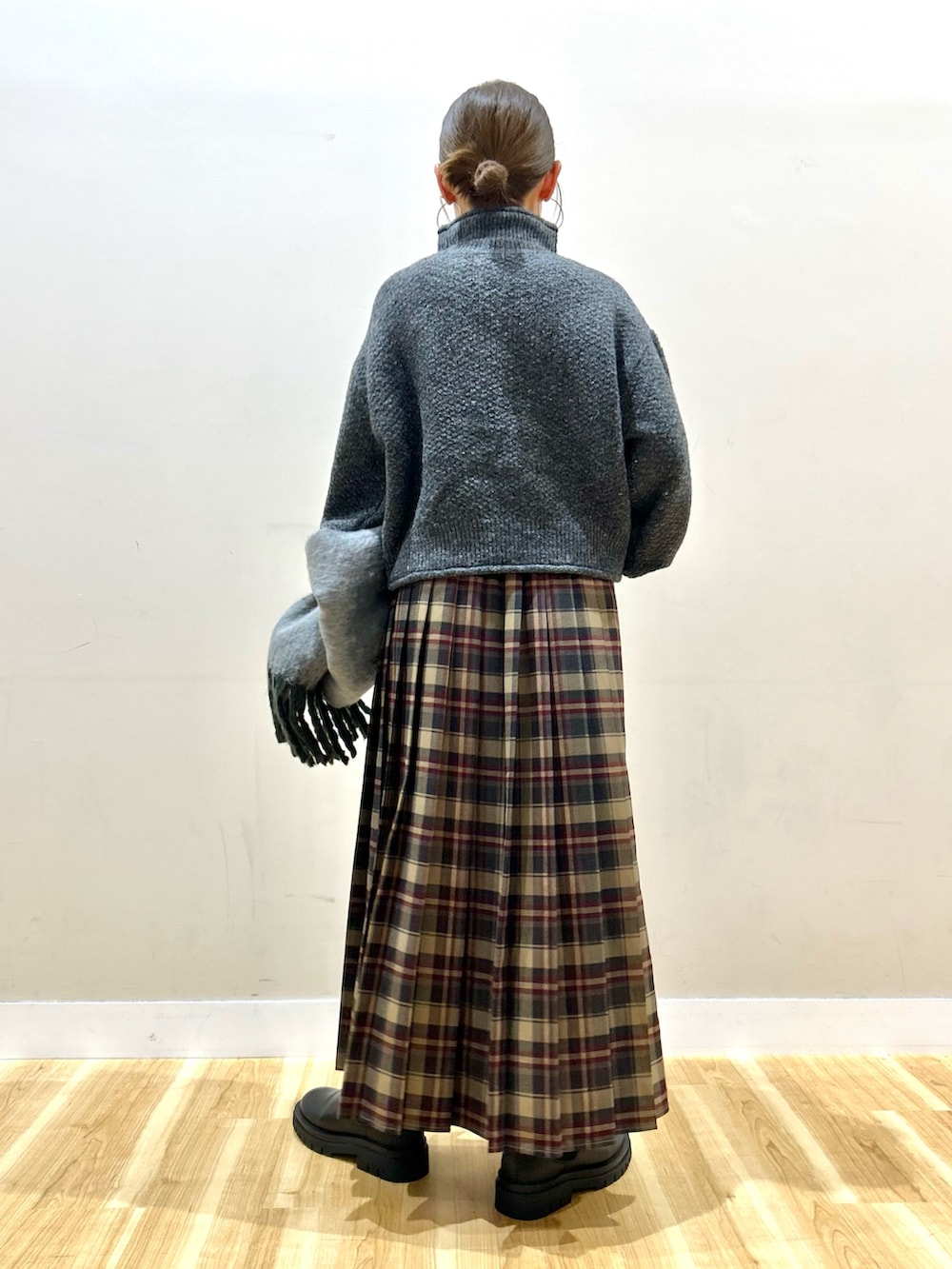 グレー系のニット/セーター、ブラウン系のスカート、ブラック系のブーツを着用したレディースの冬コーディネートの2枚目の写真