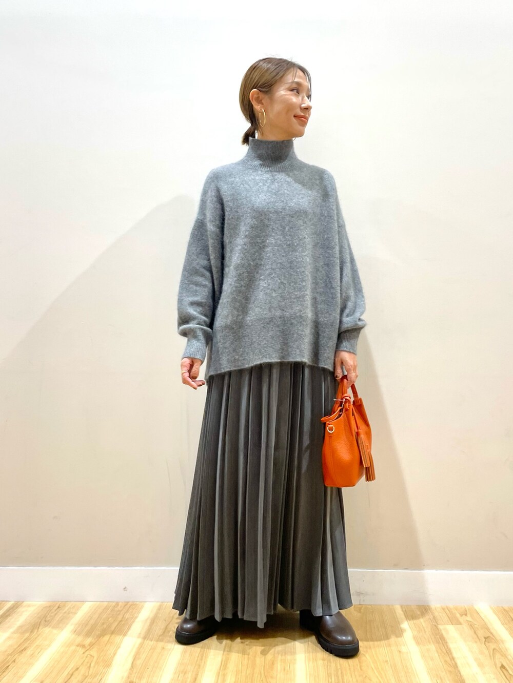 ホワイト系のダウンジャケット/コート、グレー系のニット/セーター、グレー系のスカートを着用したレディースの冬コーディネートの6枚目の写真