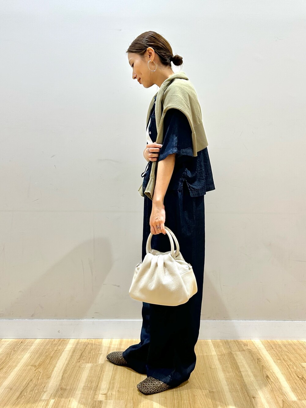 ホワイト系のTシャツ/カットソー、ブルー系のデニムパンツ、ブラウン系のハンドバッグを着用したレディースの春コーディネートの2枚目の写真