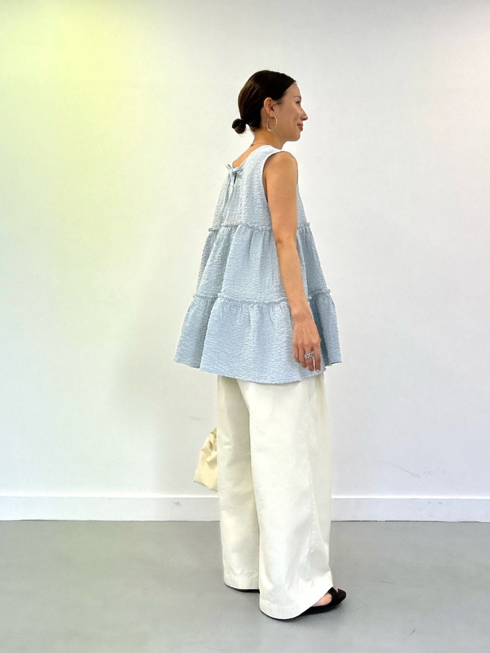 ブルー系のチュニック、ホワイト系のその他パンツ、ホワイト系のショルダーバッグを着用したレディースの春コーディネートの2枚目の写真