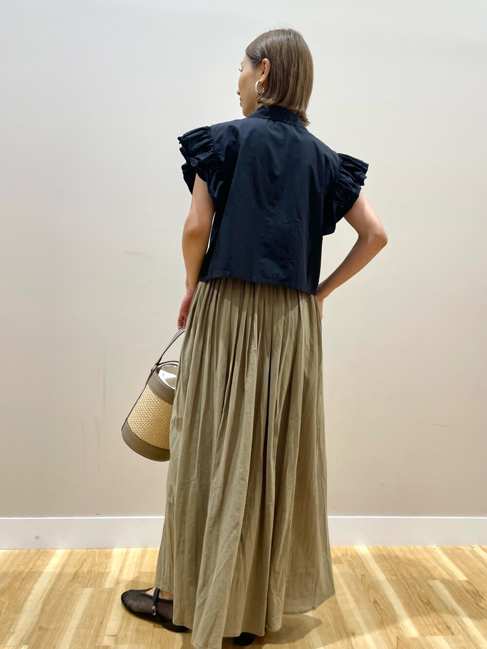 イエロー系のスカート、ブラック系のシャツ/ブラウスを着用したレディースの夏コーディネートの3枚目の写真