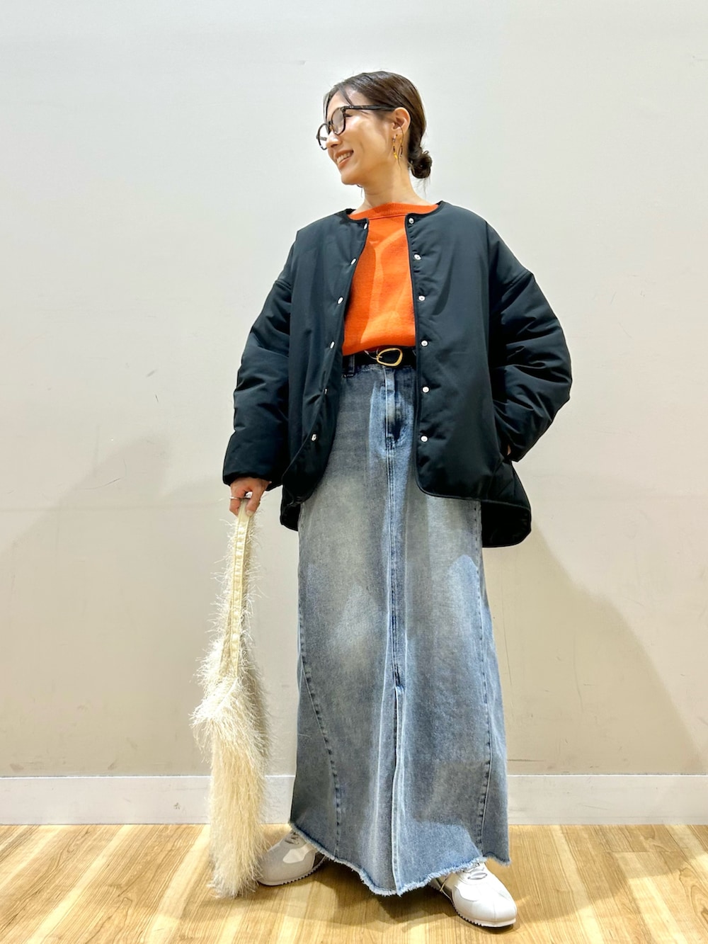 ブラック系のダウンジャケット/コート、オレンジ系のニット/セーター、ブルー系のスカートを着用したレディースの冬コーディネートの2枚目の写真