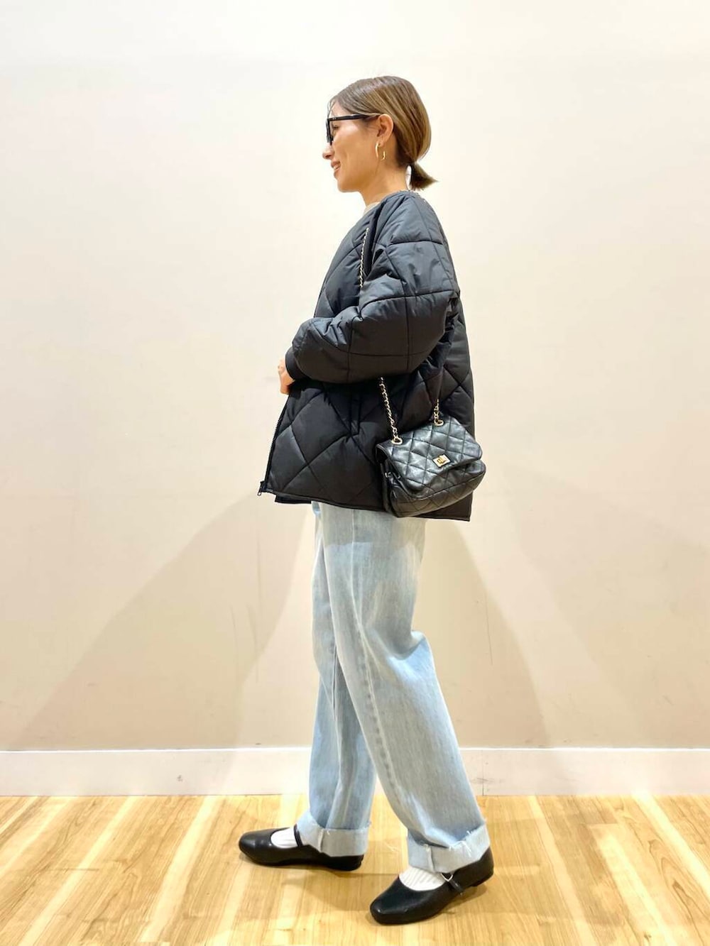 ブラック系のパンプス、ベージュ系のニット/セーター、ブルー系のデニムパンツを着用したレディースの冬コーディネートの2枚目の写真