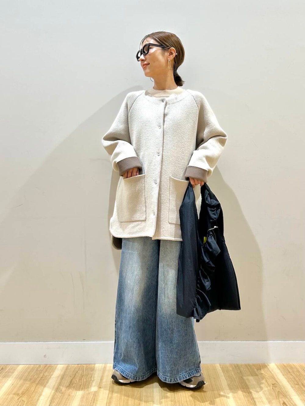 ホワイト系のニット/セーター、ブルー系のデニムパンツ、ブラック系のトートバッグを着用したレディースの春コーディネートの5枚目の写真
