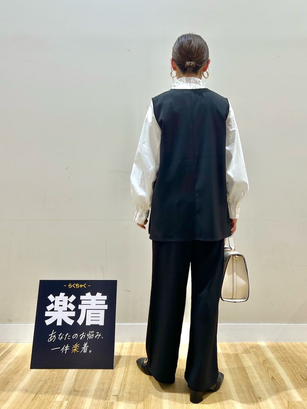 ブラック系のセットアップ、ホワイト系のシャツ/ブラウス、ホワイト系のハンドバッグを着用したレディースの春コーディネートの3枚目の写真