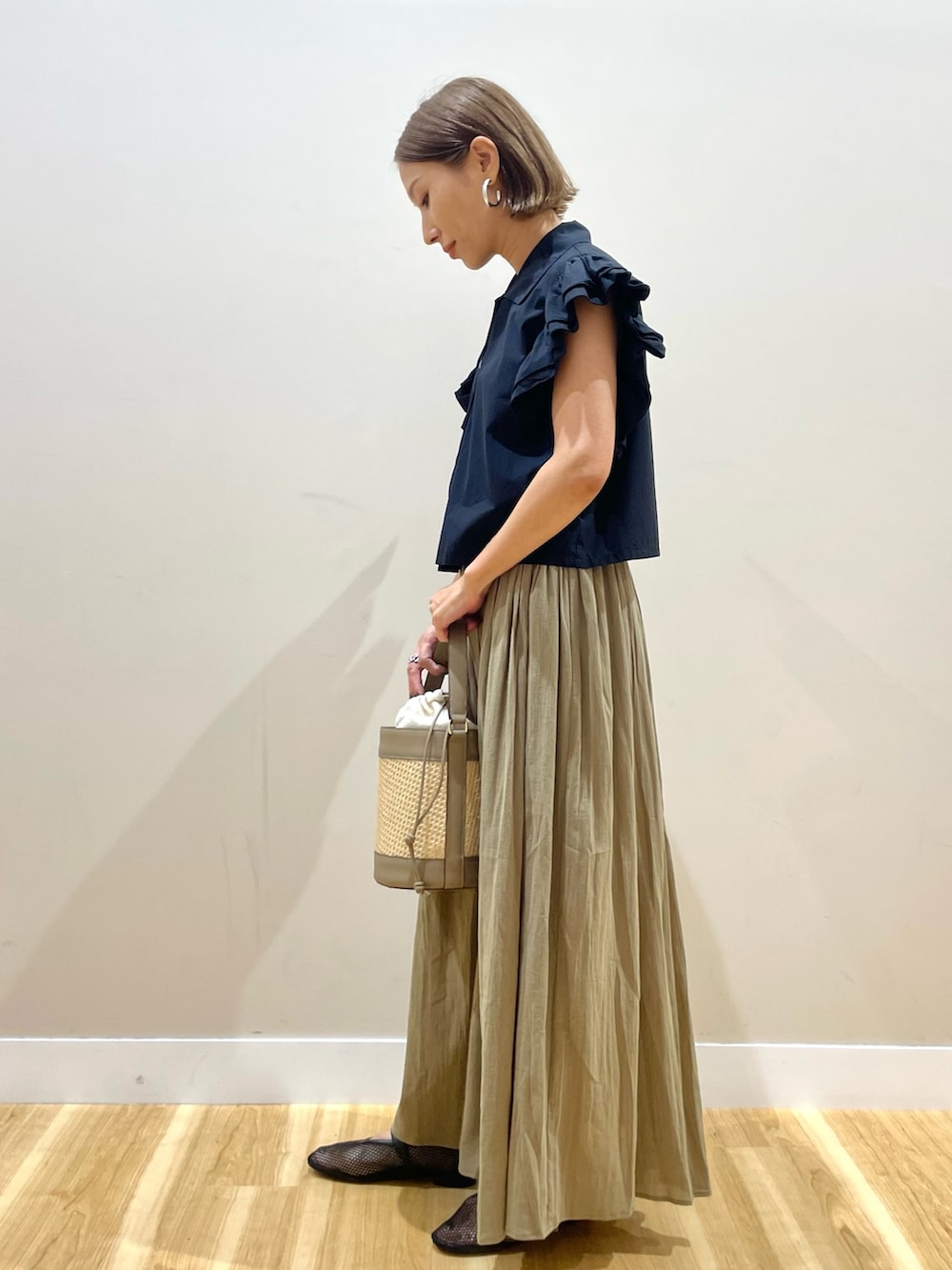 イエロー系のスカート、ブラック系のシャツ/ブラウスを着用したレディースの夏コーディネートの2枚目の写真