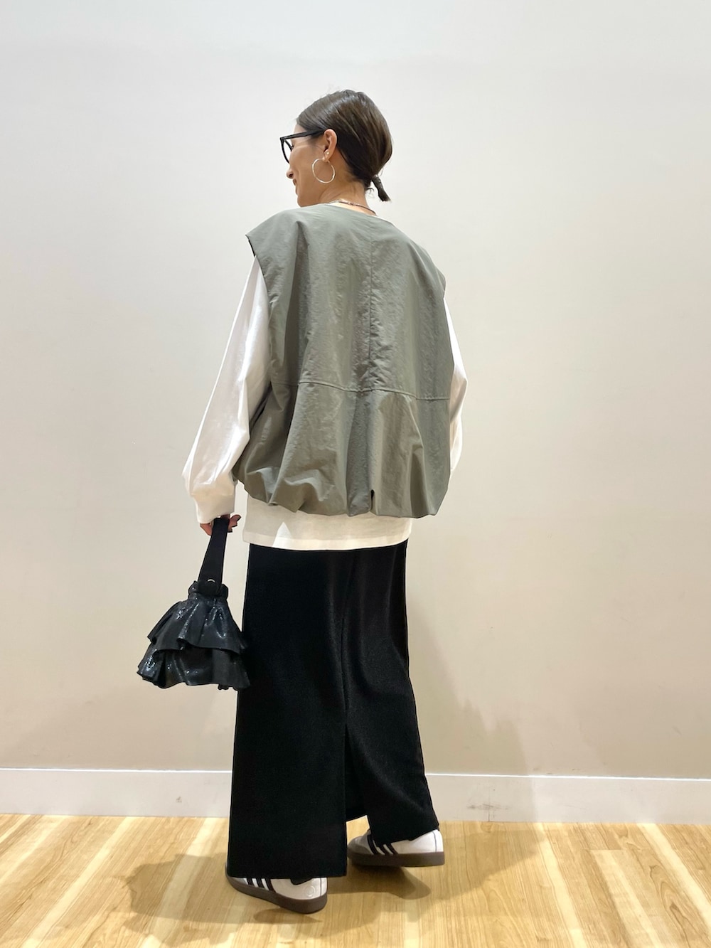 グリーン系のベスト、ホワイト系のTシャツ/カットソー、ブラック系のスカートを着用したレディースの秋コーディネートの3枚目の写真