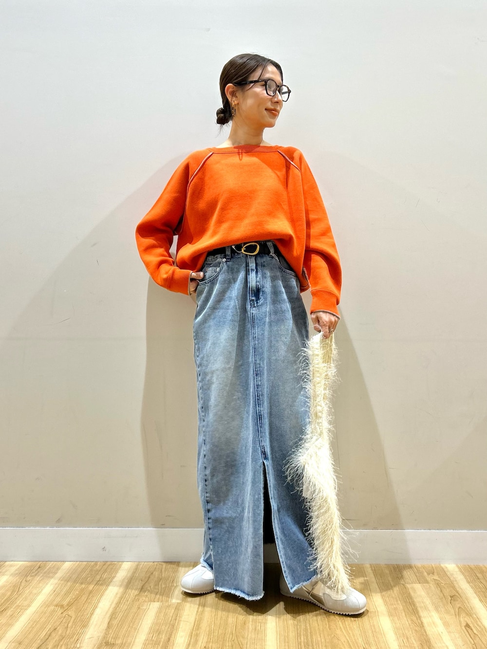 ブラック系のダウンジャケット/コート、オレンジ系のニット/セーター、ブルー系のスカートを着用したレディースの冬コーディネートの6枚目の写真