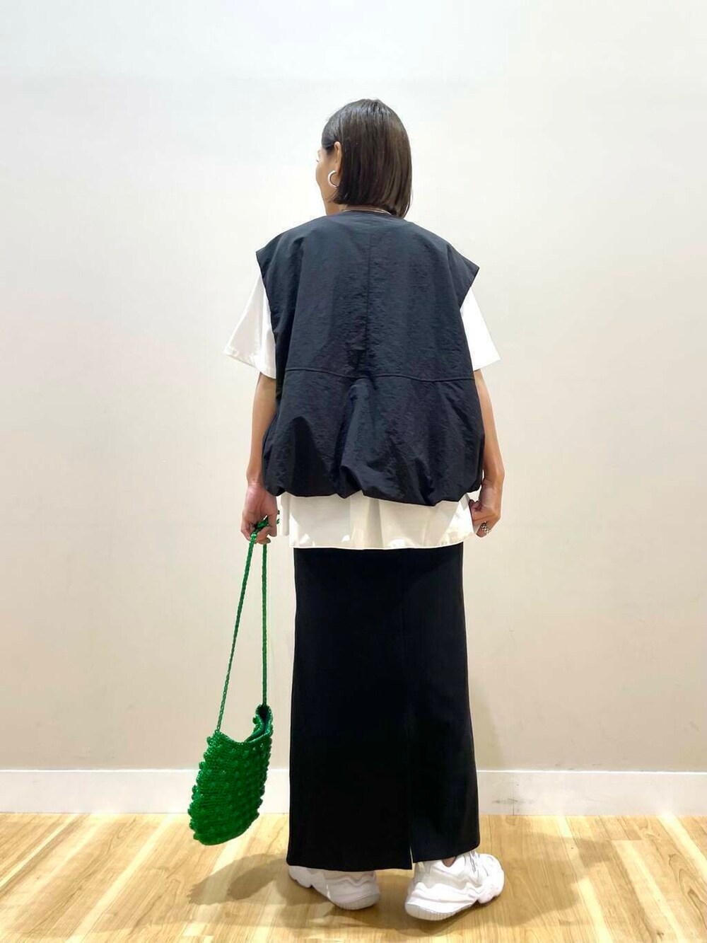 ホワイト系のスニーカー、グリーン系のショルダーバッグ、ブラック系のスカートを着用したレディースの秋コーディネートの4枚目の写真