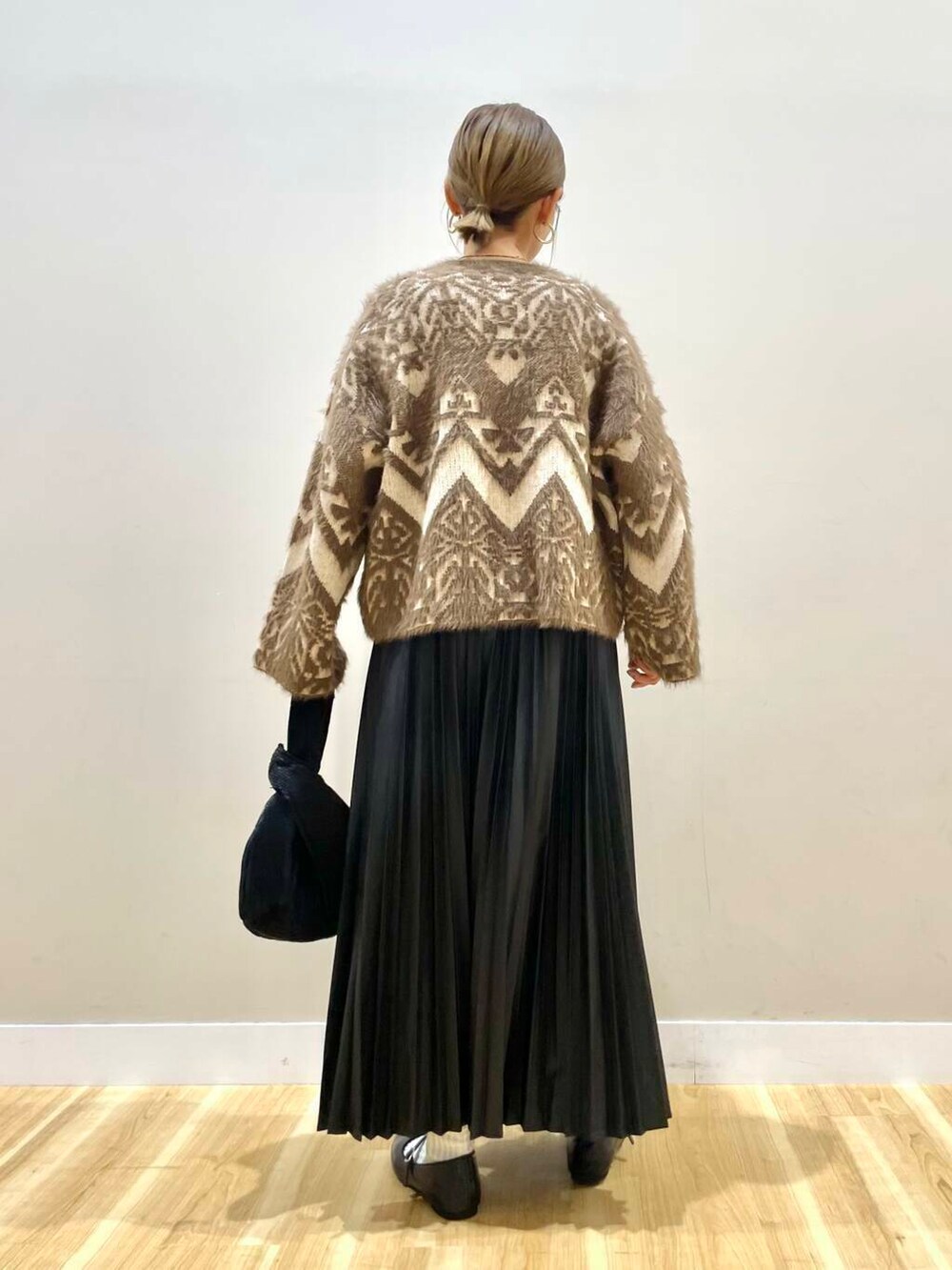 ブラック系のパンプス、ブラック系のハンドバッグ、ベージュ系のカーディガン/ボレロを着用したレディースの冬コーディネートの8枚目の写真