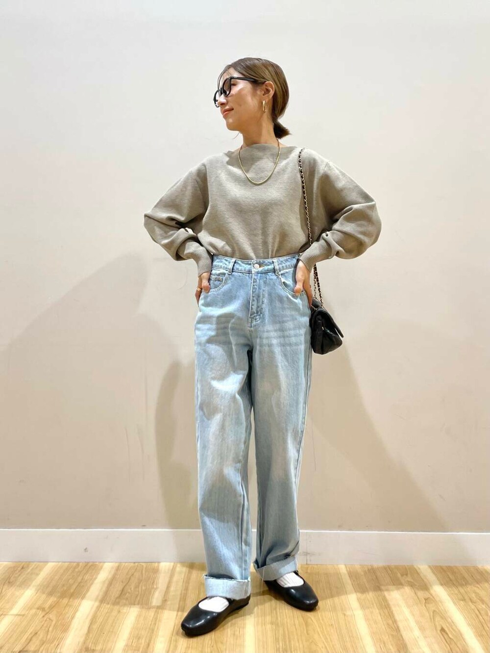 ブラック系のパンプス、ベージュ系のニット/セーター、ブルー系のデニムパンツを着用したレディースの冬コーディネートの6枚目の写真