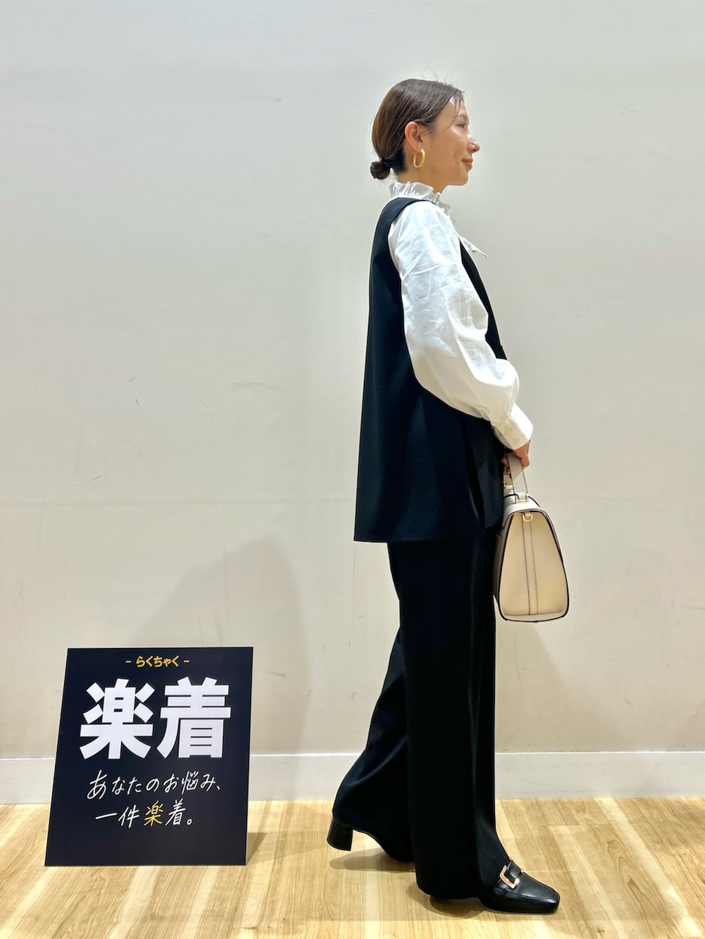 ブラック系のセットアップ、ホワイト系のシャツ/ブラウス、ホワイト系のハンドバッグを着用したレディースの春コーディネートの2枚目の写真