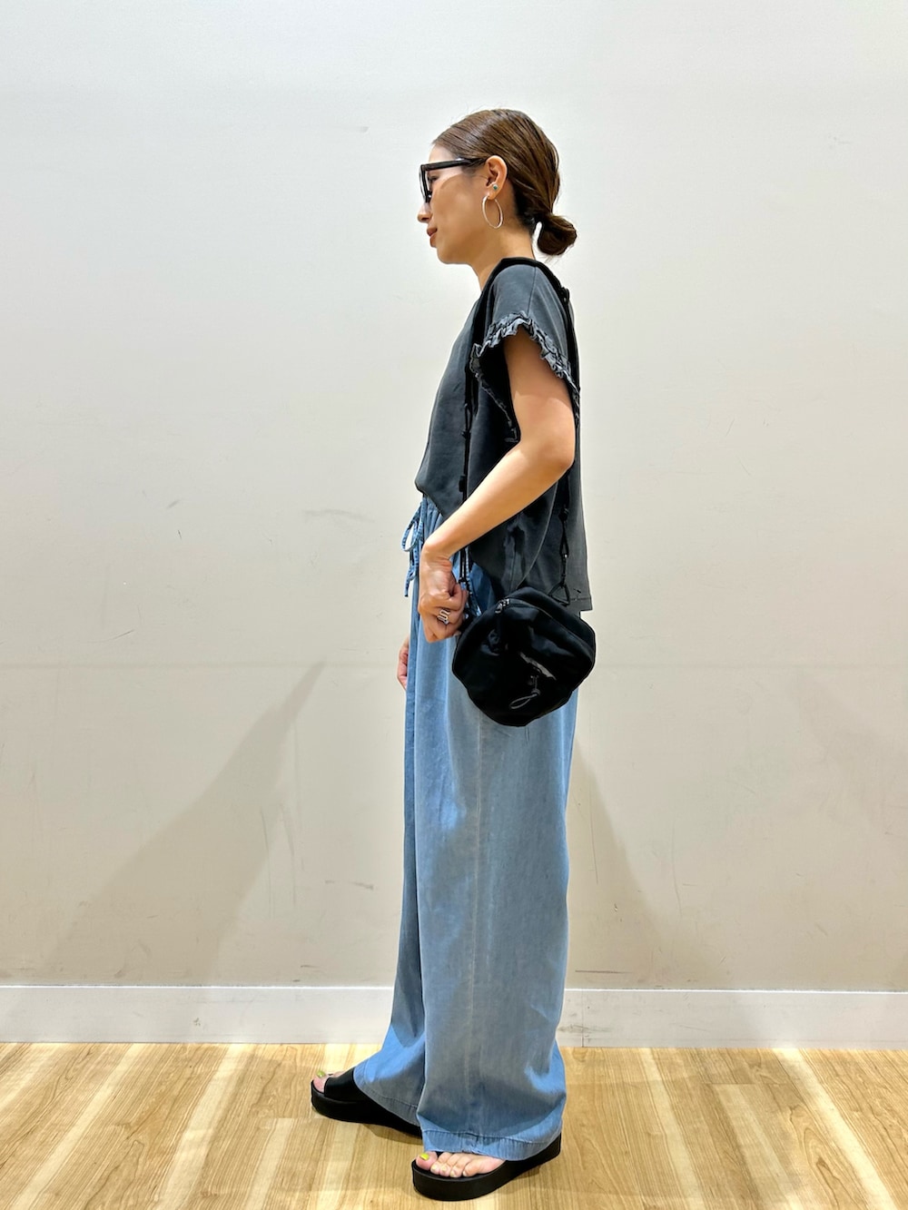 ブラック系のTシャツ/カットソー、ブルー系のデニムパンツ、ブラック系のショルダーバッグを着用したレディースの夏コーディネートの2枚目の写真
