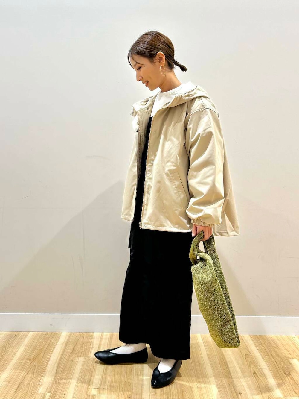 ゴールド系のトートバッグ、ベージュ系のマウンテンパーカー、ホワイト系のスウェットを着用したレディースの冬コーディネートの2枚目の写真