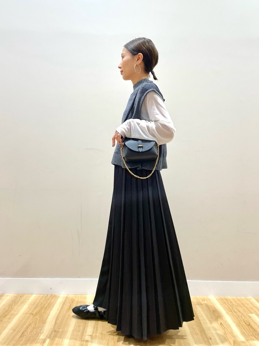 グレー系のニット/セーター、ホワイト系のTシャツ/カットソー、ブラック系のスカートを着用したレディースの秋コーディネートの2枚目の写真