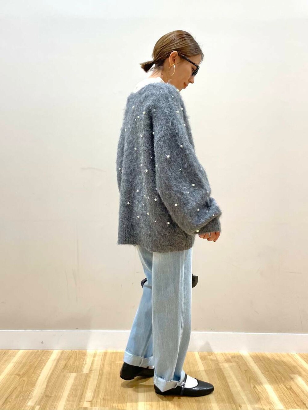 ブラック系のパンプス、ブラック系のハンドバッグ、ブルー系のデニムパンツを着用したレディースの秋コーディネートの3枚目の写真