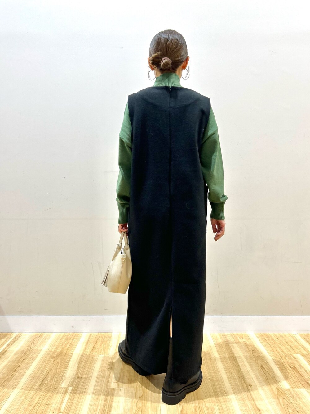 グレー系のその他アウター、グリーン系のニット/セーター、ブラック系のジャンパースカートを着用したレディースの冬コーディネートの7枚目の写真