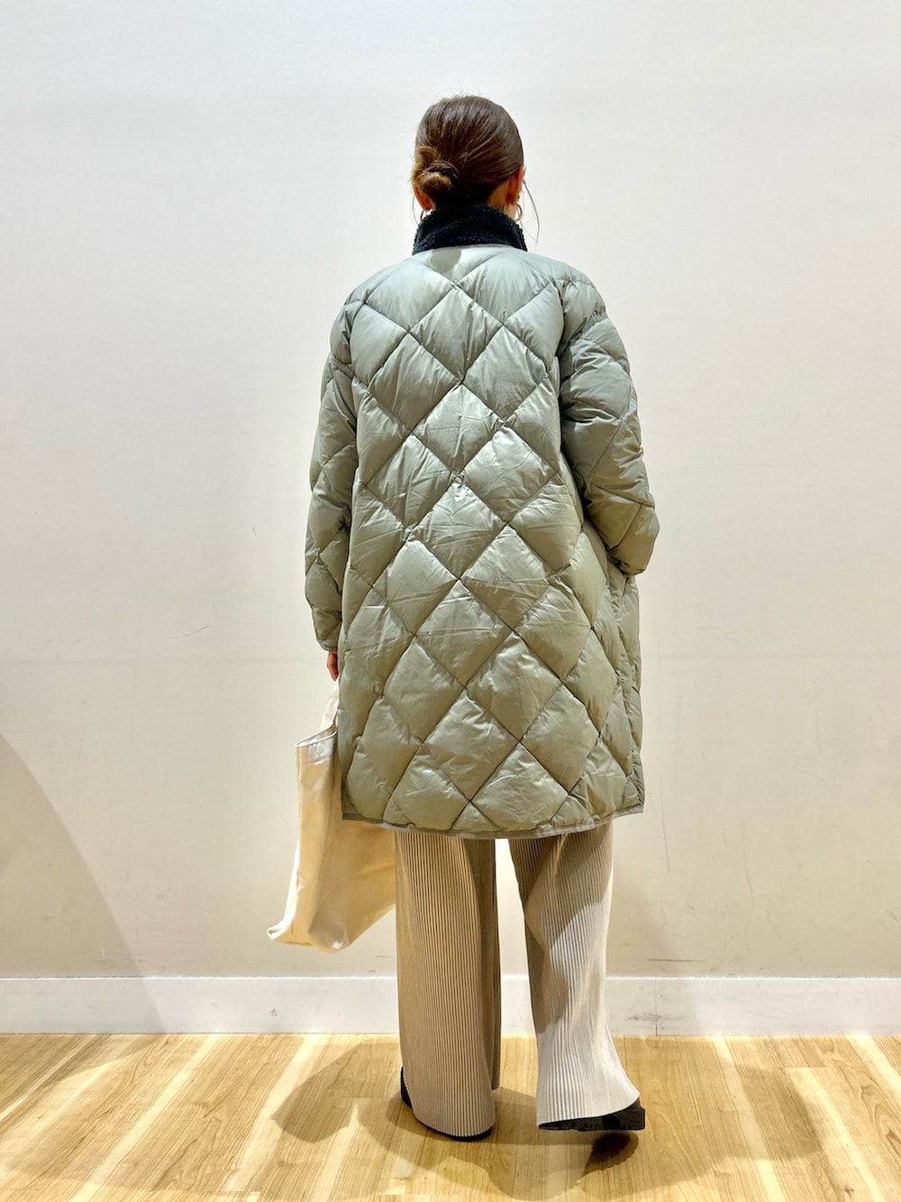 グレー系のベスト、グリーン系のダウンジャケット/コート、ホワイト系のニット/セーターを着用したレディースの冬コーディネートの3枚目の写真