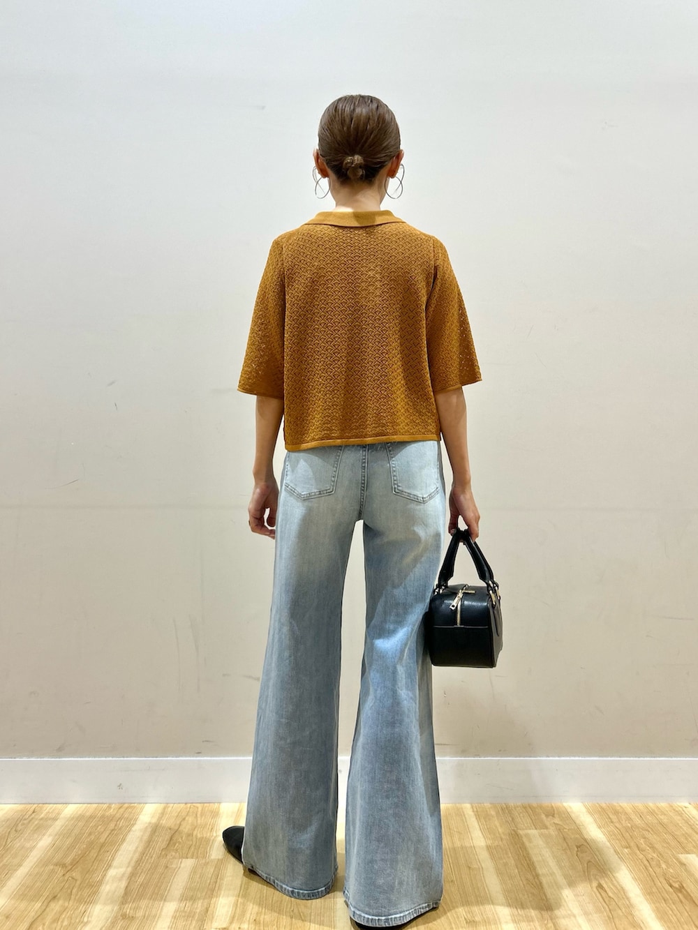 ブラウン系のニット/セーター、ブルー系のデニムパンツ、ブラック系のハンドバッグを着用したレディースの夏コーディネートの4枚目の写真