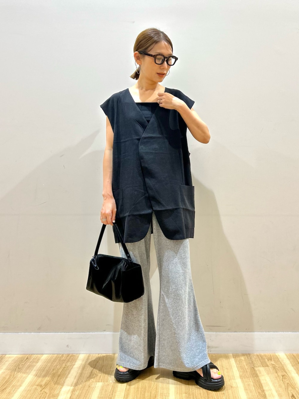 ブラック系のダウンベスト、グレー系のその他パンツ、ブラック系のトートバッグを着用したレディースの夏コーディネートの2枚目の写真