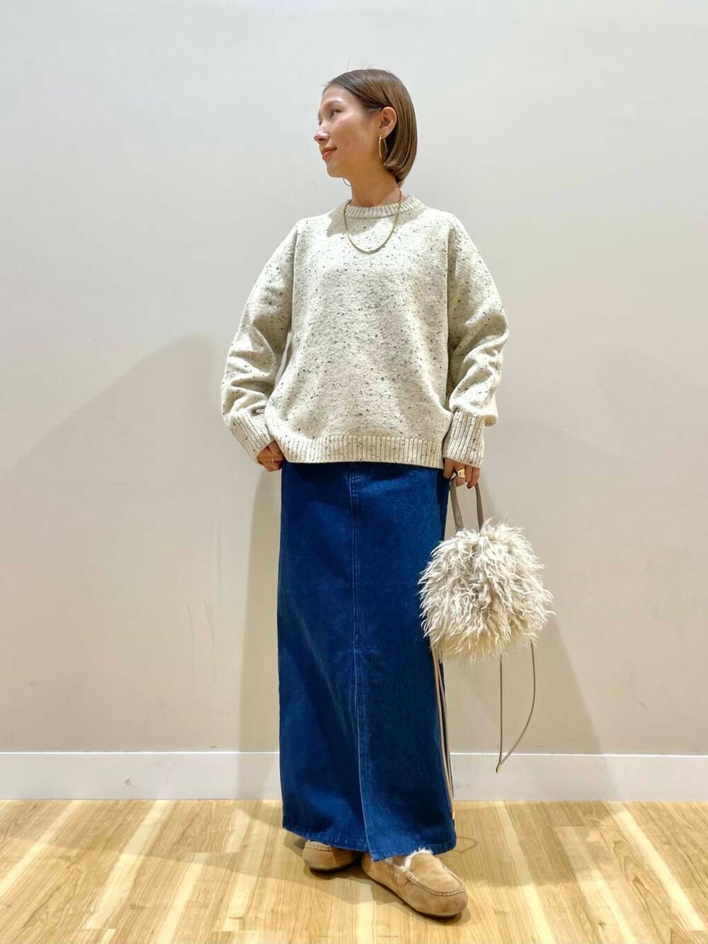 ベージュ系のショルダーバッグ、ブルー系のスカート、ベージュ系のダウンジャケット/コートを着用したレディースの秋コーディネートの6枚目の写真