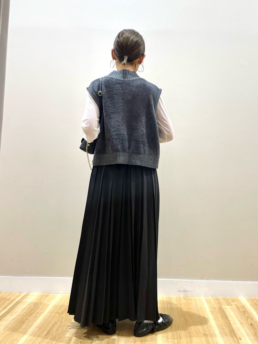 グレー系のニット/セーター、ホワイト系のTシャツ/カットソー、ブラック系のスカートを着用したレディースの秋コーディネートの3枚目の写真