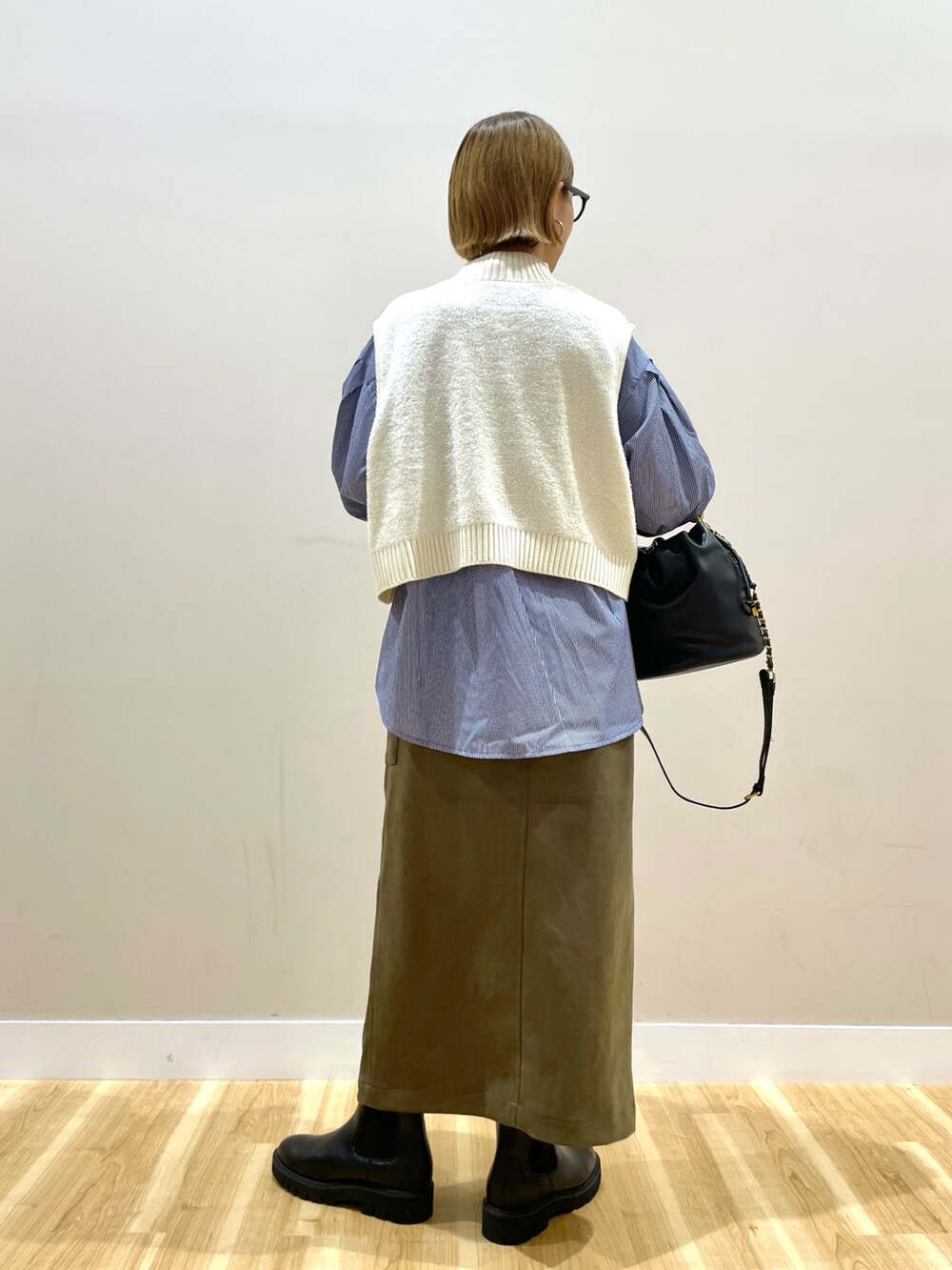 ホワイト系のニット/セーター、ブルー系のシャツ/ブラウス、グリーン系のスカートを着用したレディースの秋コーディネートの3枚目の写真