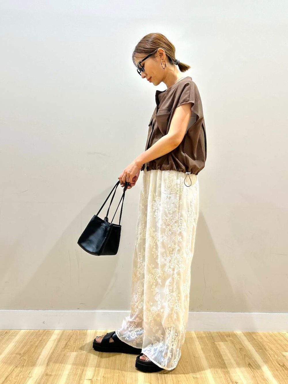 ホワイト系のその他パンツ、ブラック系のハンドバッグ、ブラック系のサンダルを着用したレディースの夏コーディネートの2枚目の写真
